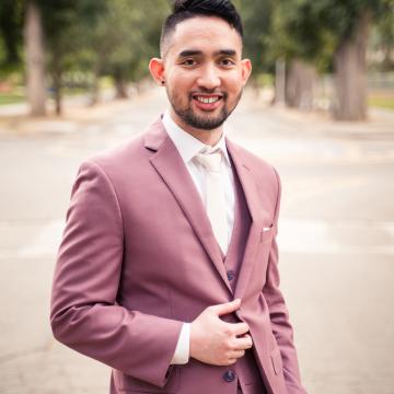 Prof. Peter Torres, a young man with dark hair and close-trimmed beard wearing a plum colored suit and white shirt